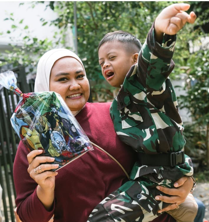 Smiling mother holding her young boy with special needs in her arms