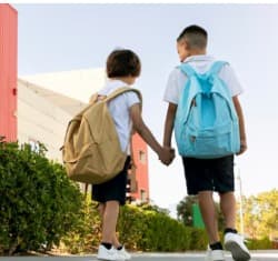 Two young school students holding hands with backpacks