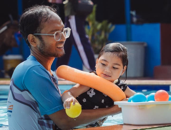 Instructor and young child with autism playing with floatie in pool